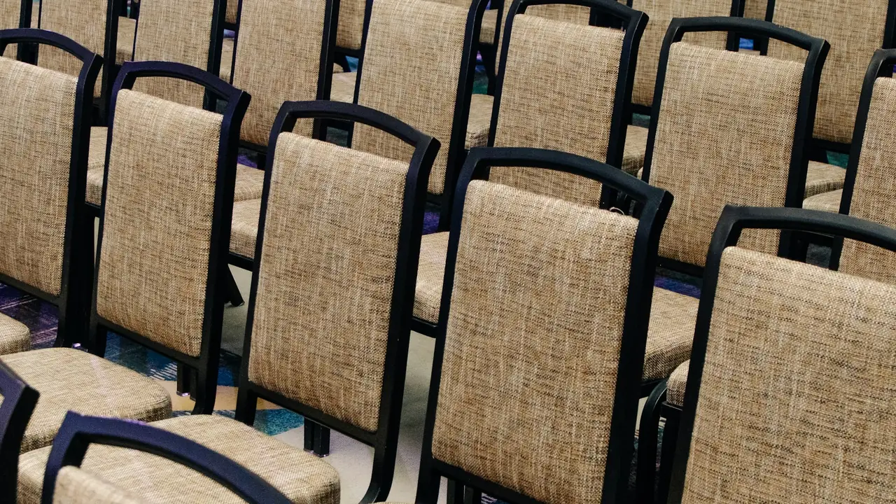 Rangées de chaises tapissées noires et beiges alignées dans une salle de conférence vide