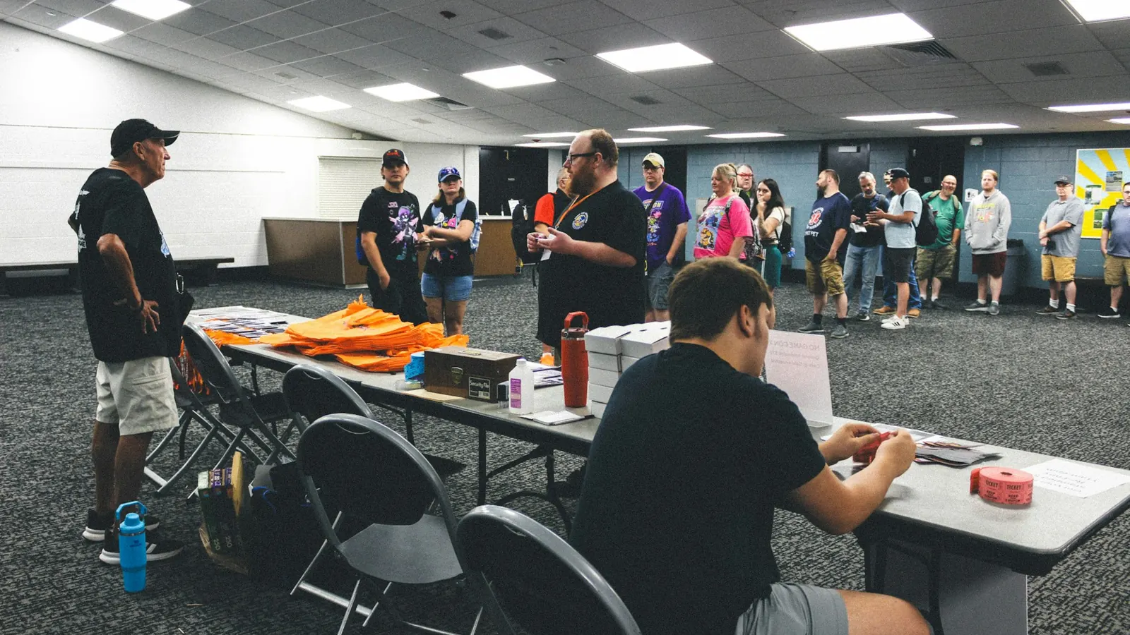 Staff and attendees at registration tables in a large room as check-in gets under way