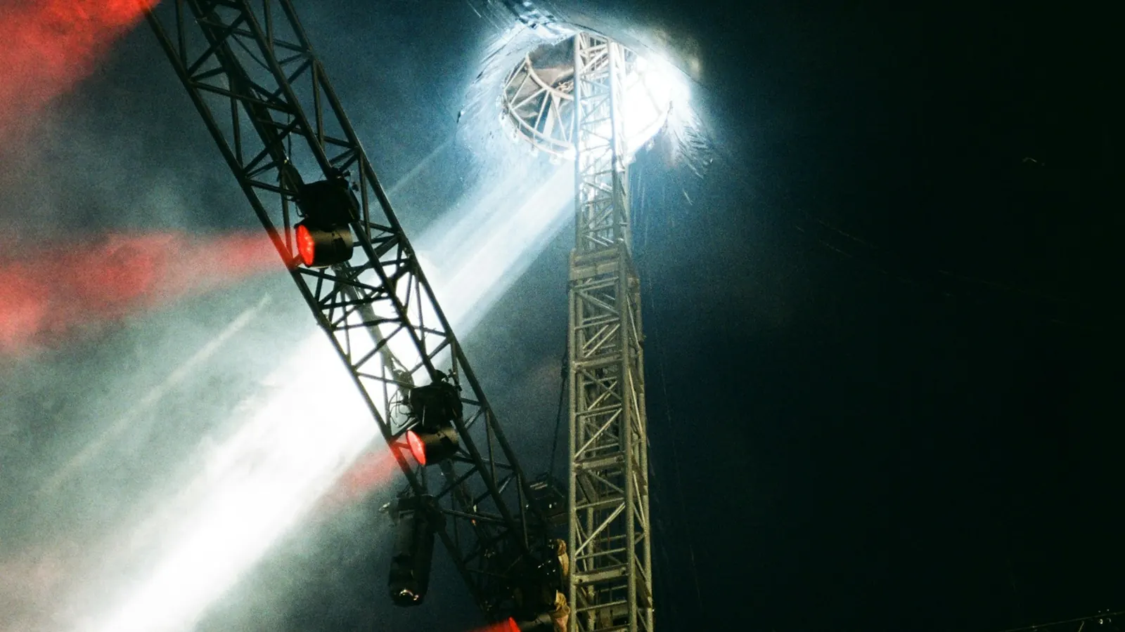 White and red stage lights shining through haze on a metal truss